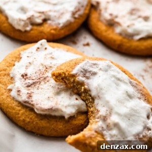 Five beautifully frosted soft pumpkin cookies, invitingly arranged on a clean white background, showcasing their delicious appeal.