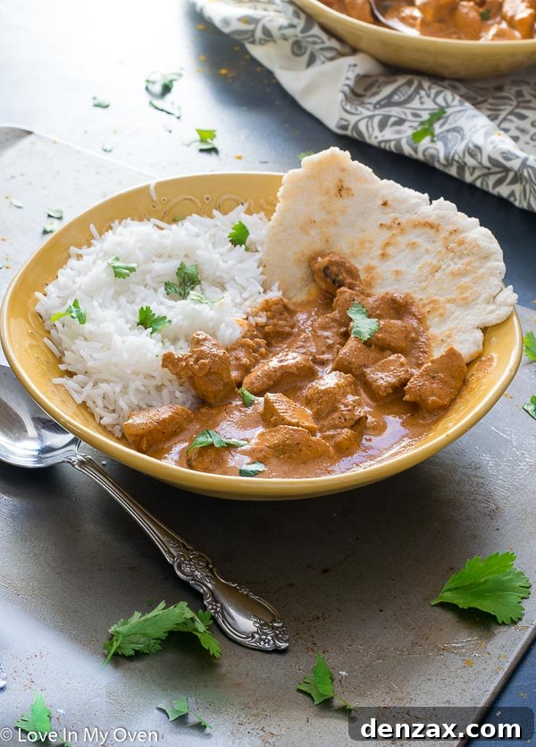 Close-up of a spoonful of Chicken Tikka Masala, showcasing its tender chicken and luscious sauce.