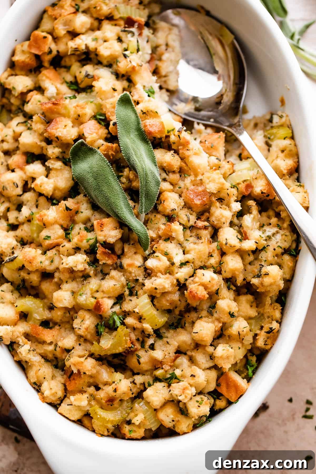 An inviting overhead shot of the freshly baked herb stuffing, golden brown and garnished with fresh sage leaves, ready to be served from a elegant white casserole dish.