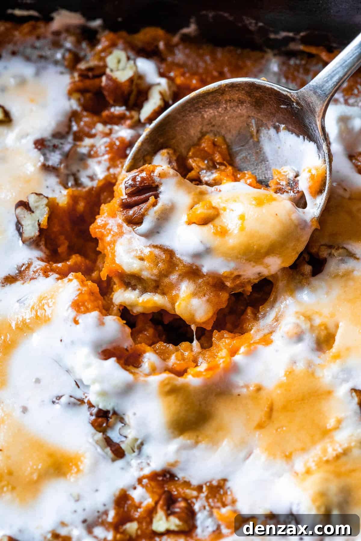 A close-up view of the sweet potato casserole, showcasing the smooth, creamy texture of the sweet potato base beneath the perfectly melted and toasted marshmallow topping.