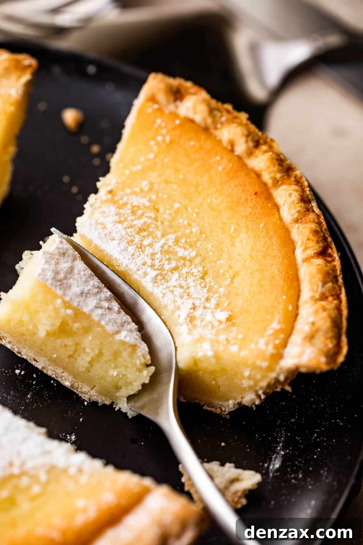 A perfectly portioned slice of Southern Buttermilk Pie, presented artfully on an elegant earthenware saucer, accompanied by a small dessert fork.