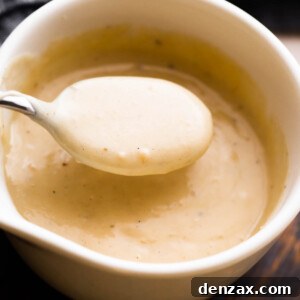 overhead shot of a white ceramic cup filled with homemade cream of chicken soup and a spoon scooping out the soup.