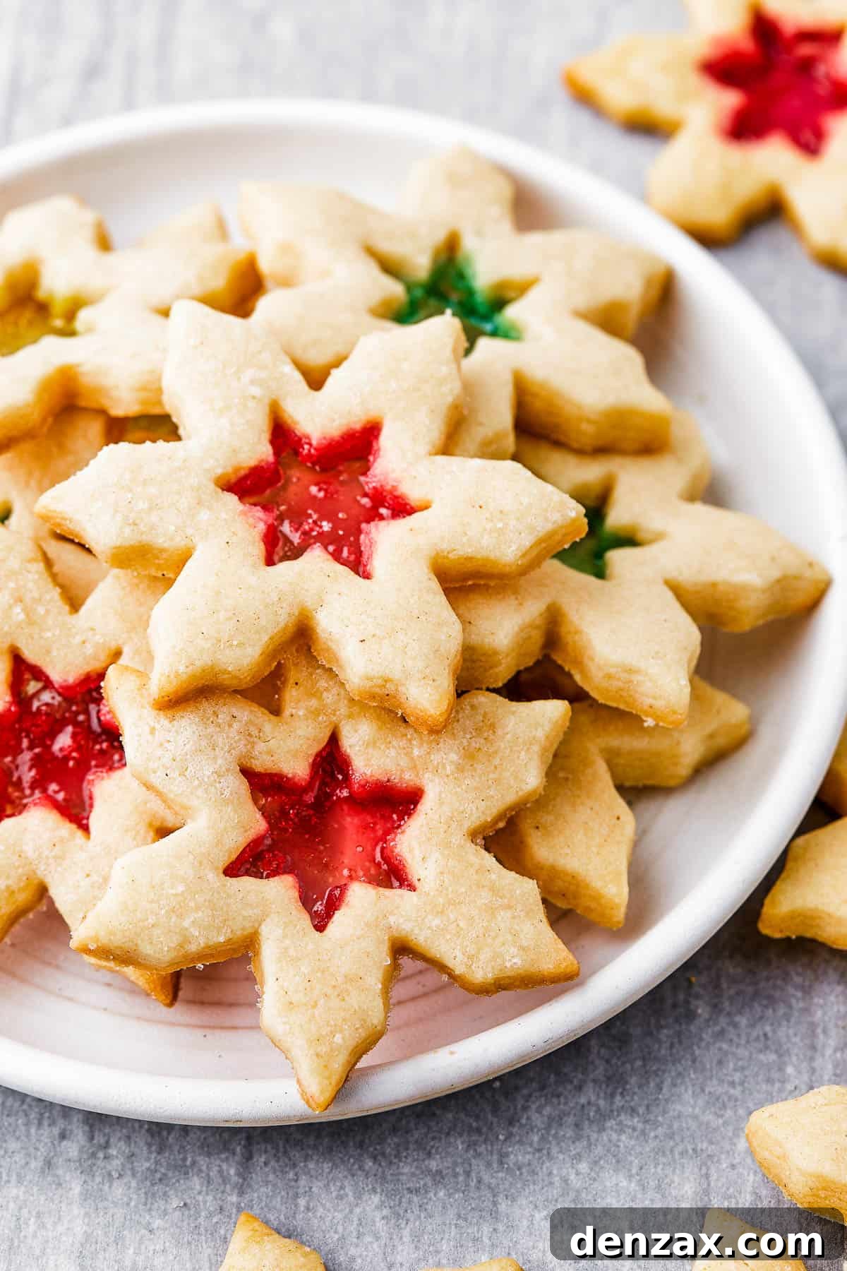 Snowflake-shaped sugar cookies with red and green centers on a round white plate.