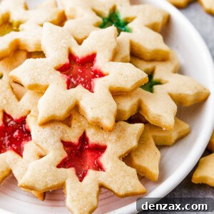 Snowflake-shaped sugar cookies with red and green centers on a round white plate.