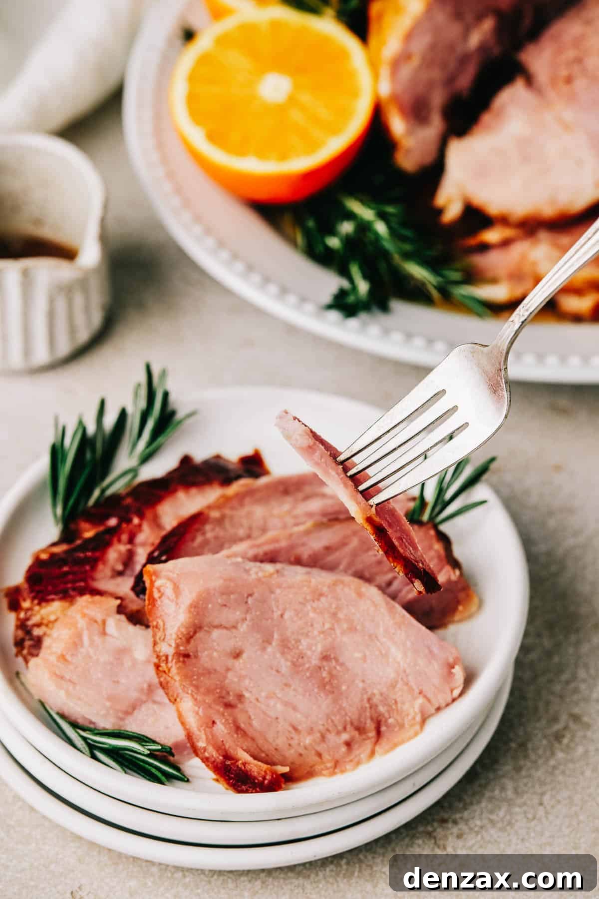 A fork lifting a slice of ham from a small plate.