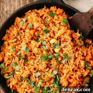 Overhead shot of a pan of spanish rice with a wooden utensil in the pan.