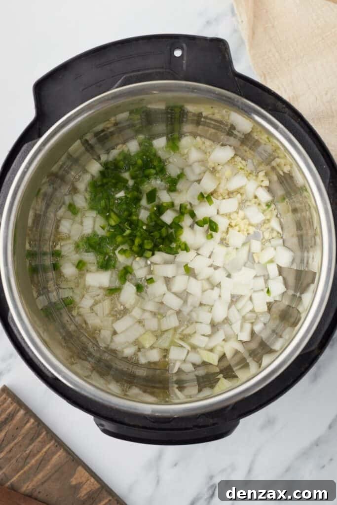 Instant Pot Fiesta Rice 5 Overhead shot of an Instant Pot, with onions, garlic, and jalapeno inside.