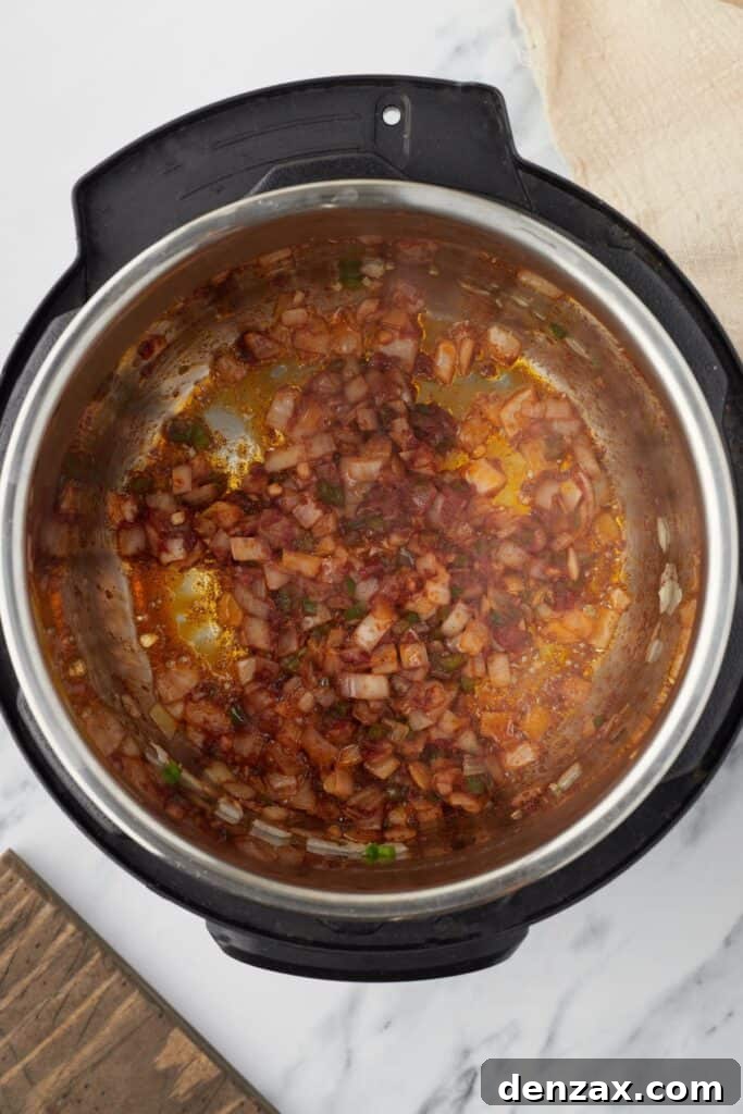 Instant Pot Fiesta Rice 6 Overhead shot of an Instant Pot with vegetables and tomato paste sauteing.