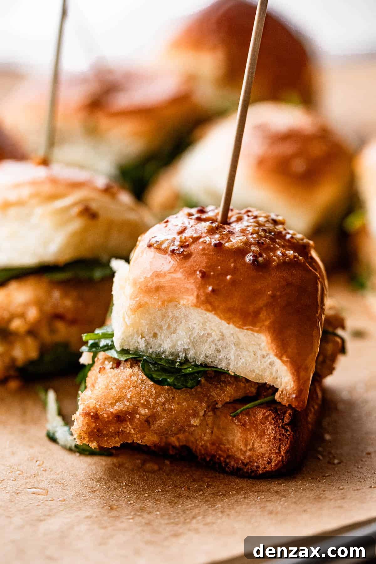 A close-up side view of a perfectly assembled Crab Cake Slider, highlighting the golden-brown crab cake nestled within a soft Hawaiian roll.