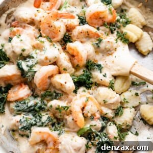 overhead shot of a steel skillet filled with gnocchi, shrimp, and greens.