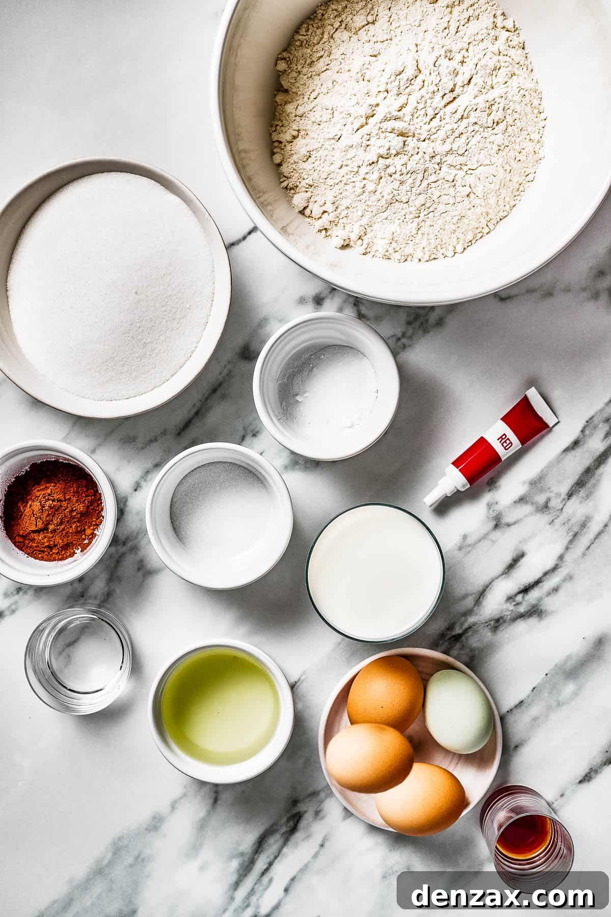 From top left: Sugar, baking soda, flour, cocoa powder, salt, milk, red food coloring, vinegar, oil, eggs, vanilla.