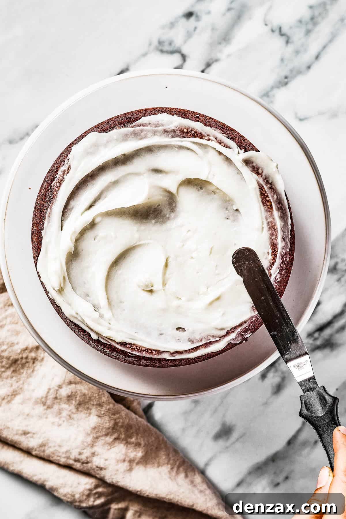 Overhead shot of a cake being frosted with an offset spatula.