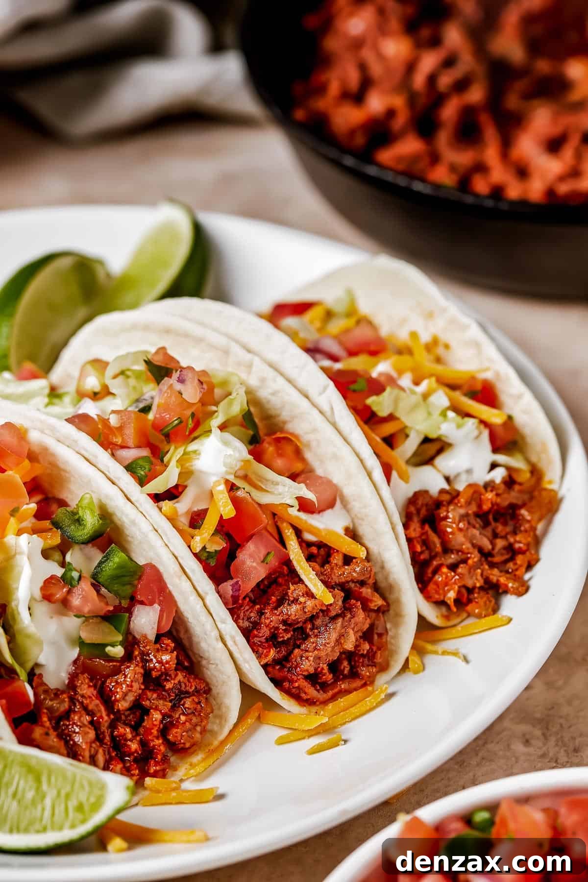 Three soft tacos elegantly arranged on a plate, garnished with fresh lime wedges, illustrating the recipe's simple yet enticing presentation.