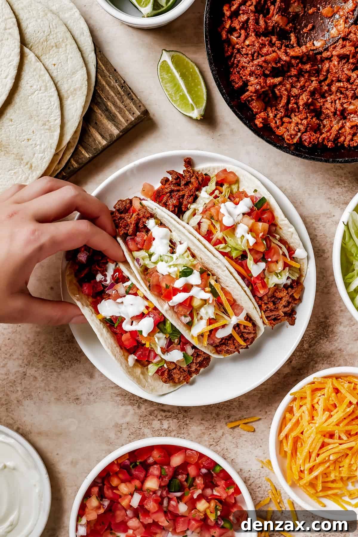 A woman's hand gracefully lifts a soft taco from a plate, highlighting the delicious and ready-to-eat nature of the meal.