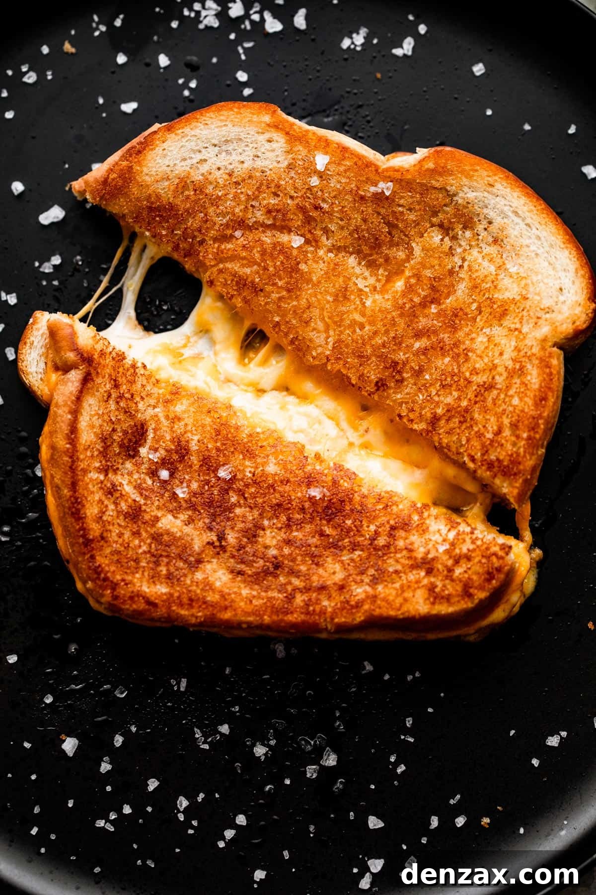 A baked grilled cheese sandwich, cut and pulled apart, with melted cheese stretching beautifully from the center.