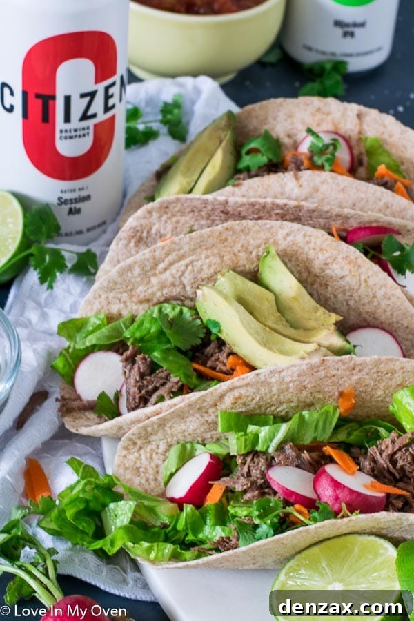 Finished Instant Pot barbacoa beef tacos with various fresh toppings