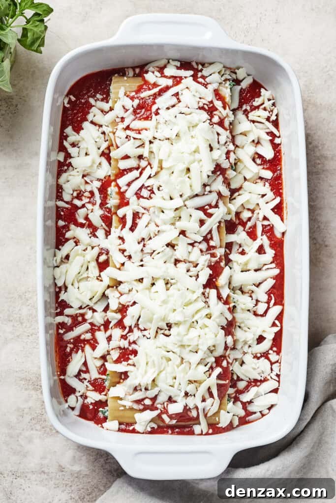 A pasta casserole dish, still in the baking process, sprinkled with a generous layer of cheese.