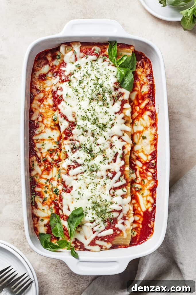 A perfectly baked pasta dish, topped with melted, bubbly cheese and garnished with fresh green herbs.