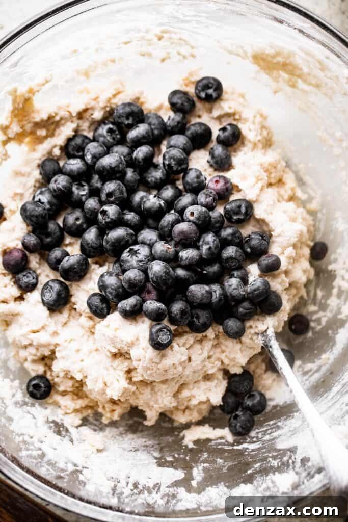 folding blueberries into a batter for blueberry scones