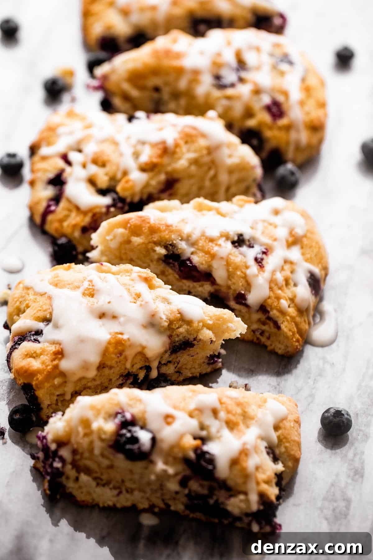 six blueberry scones arranged in a single row on a marble board