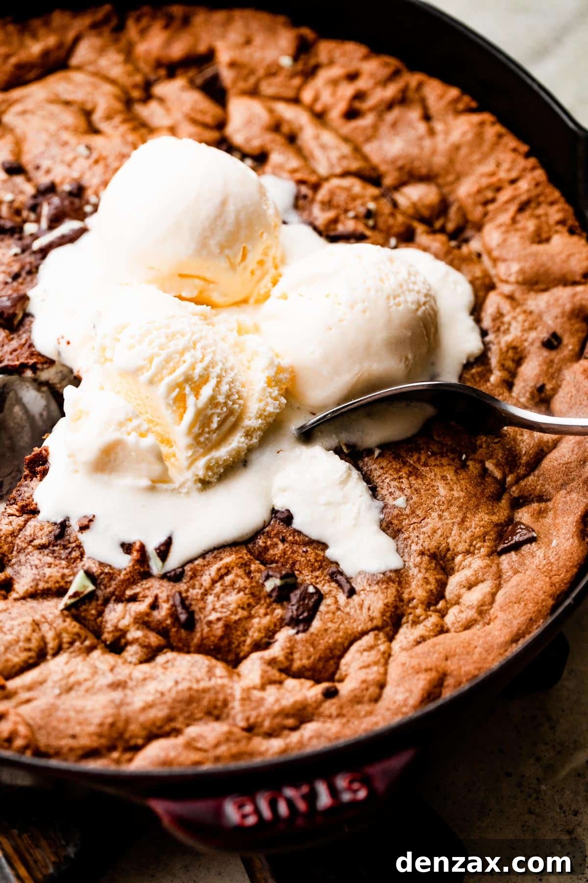 close up overhead shot of three vanilla ice cream scoops set on top of a large skillet cookie.