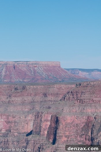 A scenic view of the Grand Canyon with a small helicopter visible in the distance, emphasizing the immense scale of the natural wonder.