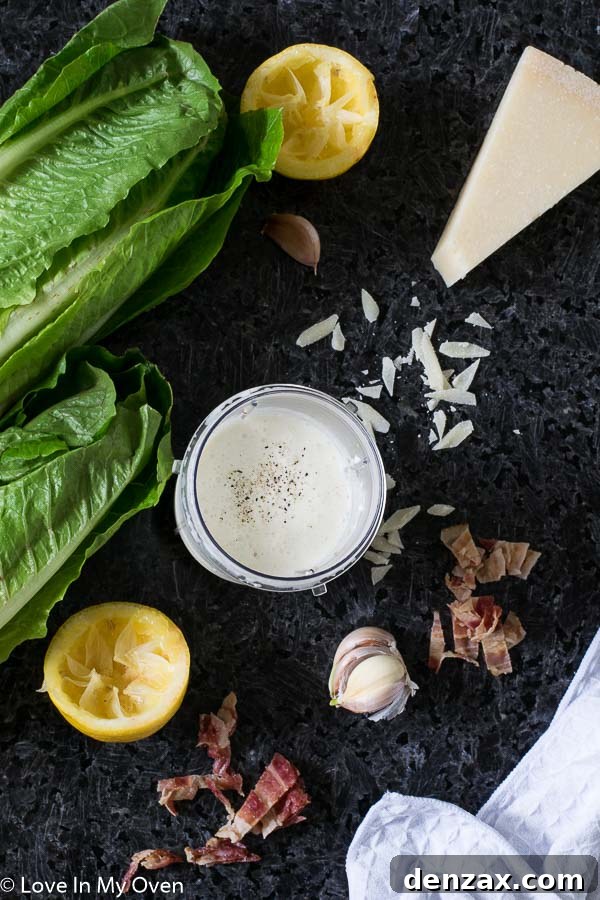 caesar dressing in a glass jar, with fresh parmesan and garlic cloves around it, illustrating its homemade goodness.