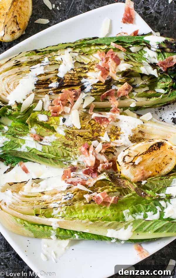 A large serving of grilled romaine Caesar salad on a wooden board, garnished with lemon wedges and fresh herbs, ready to be served.