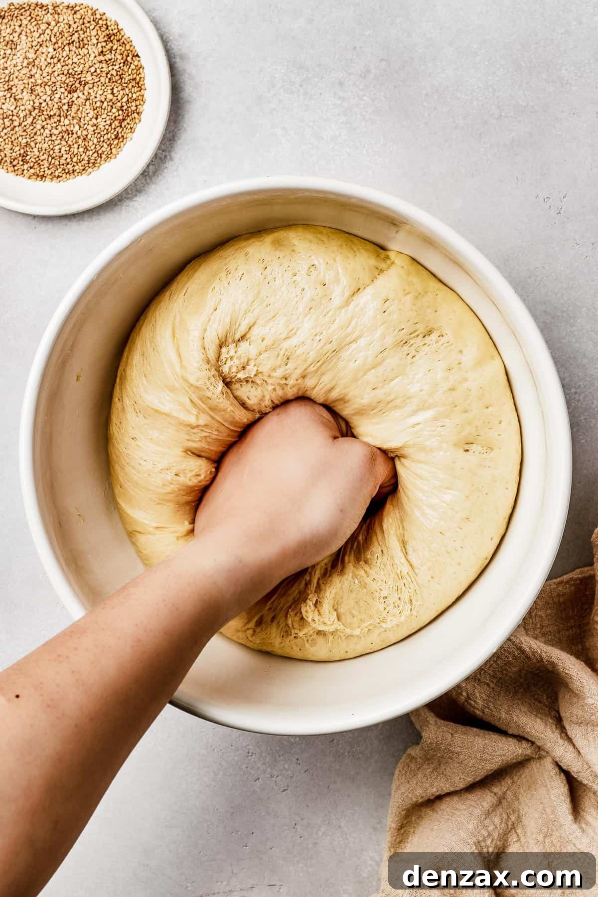 Risen bread dough being punched down in the center.