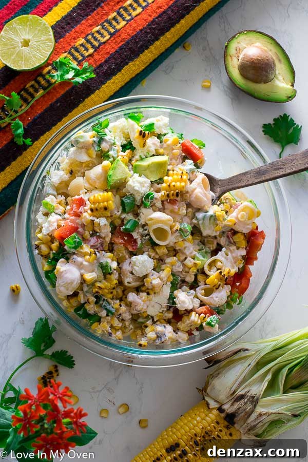 Vibrant Mexican Street Corn Pasta Salad in a large bowl, garnished with cilantro and lime wedges