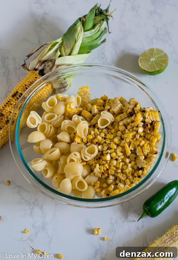 Close-up of Mexican Street Corn Pasta Salad ingredients being mixed in a bowl