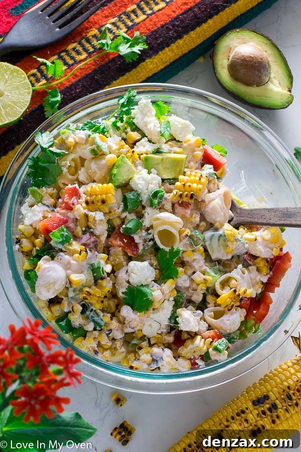 Large bowl of Mexican Street Corn Pasta Salad, garnished with fresh cilantro and lime