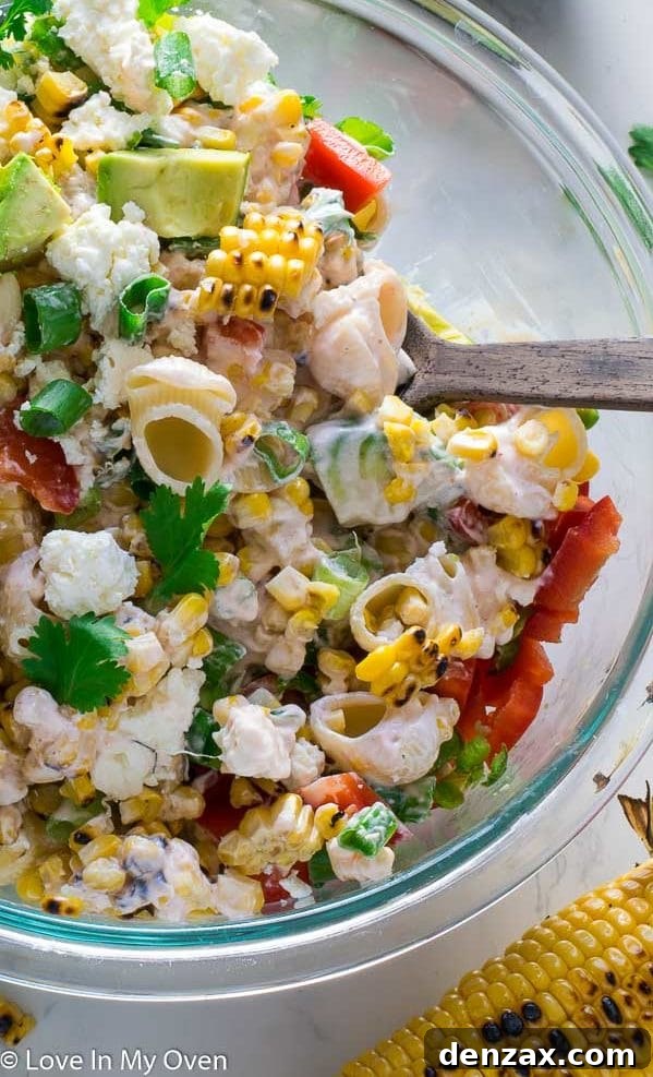 A close-up of a serving of creamy Mexican Street Corn Pasta Salad with fresh cilantro and lime