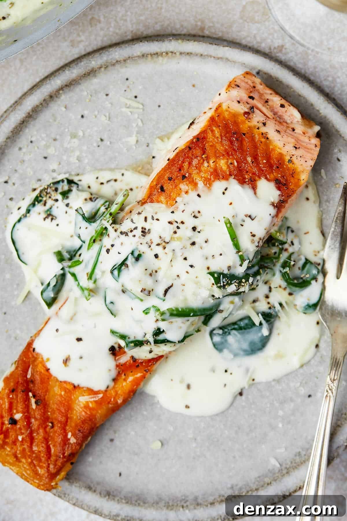 Creamy Florentine Salmon 10 A salmon fillet topped with creamy sauce on a small plate.