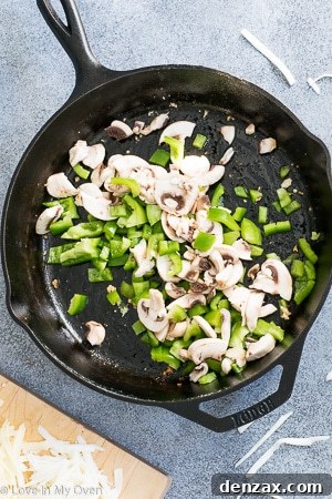 Diced peppers and mushrooms sautéing in a cast iron skillet