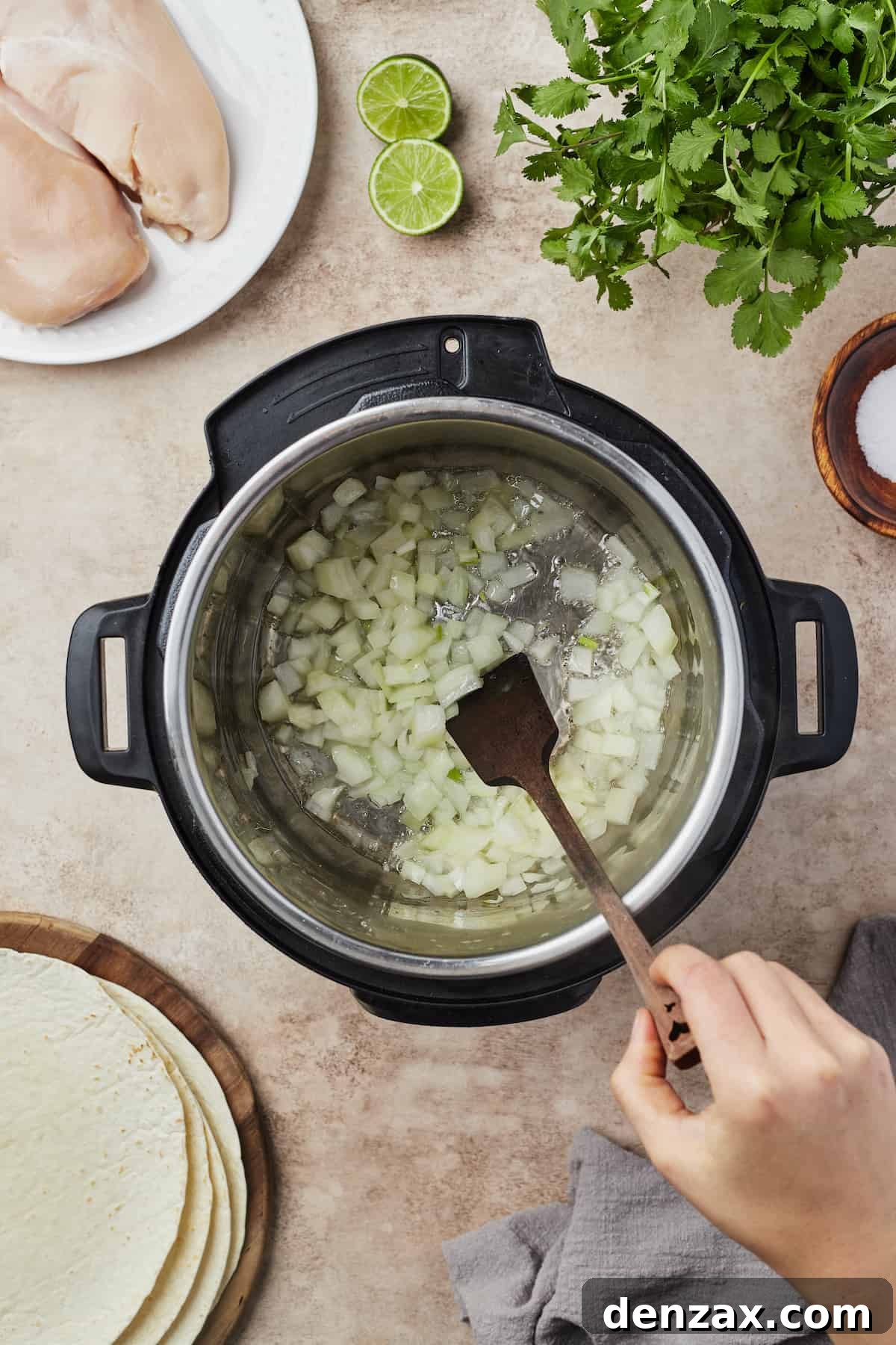 Overhead shot of diced yellow onions being sautéed until translucent in the Instant Pot, preparing a flavorful base for the burritos.