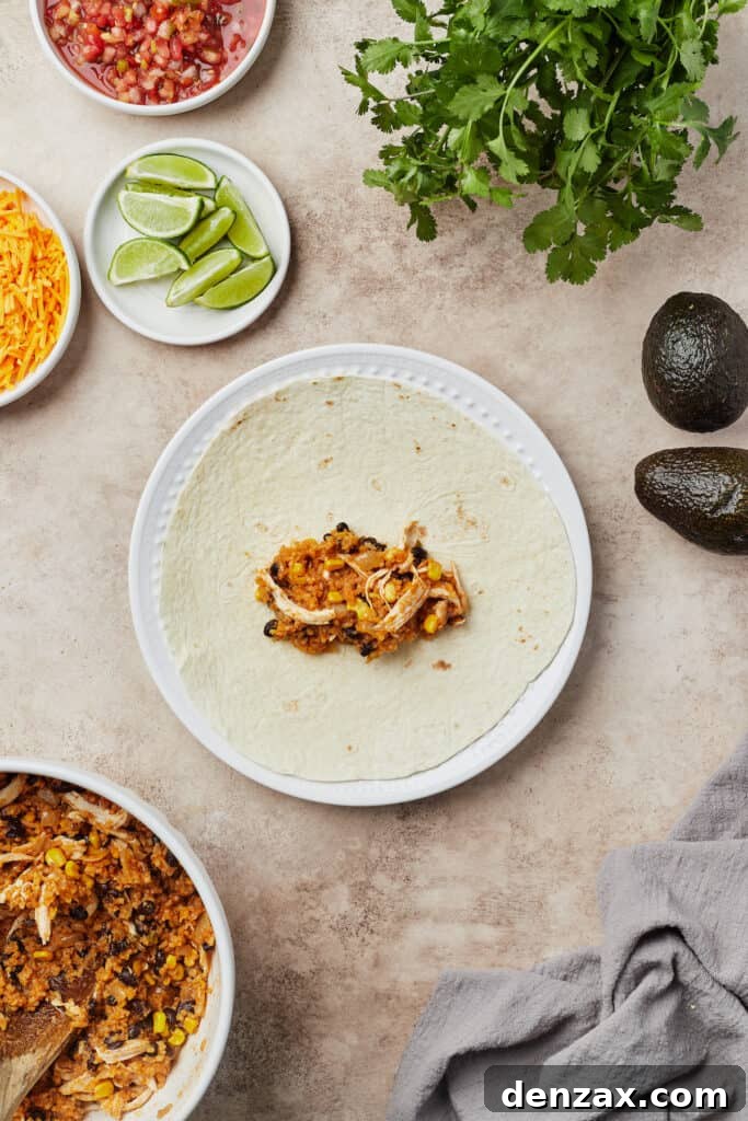 A soft flour tortilla laid flat on a plate, with a generous mound of the Instant Pot chicken and rice burrito filling neatly piled in its center, ready for folding.