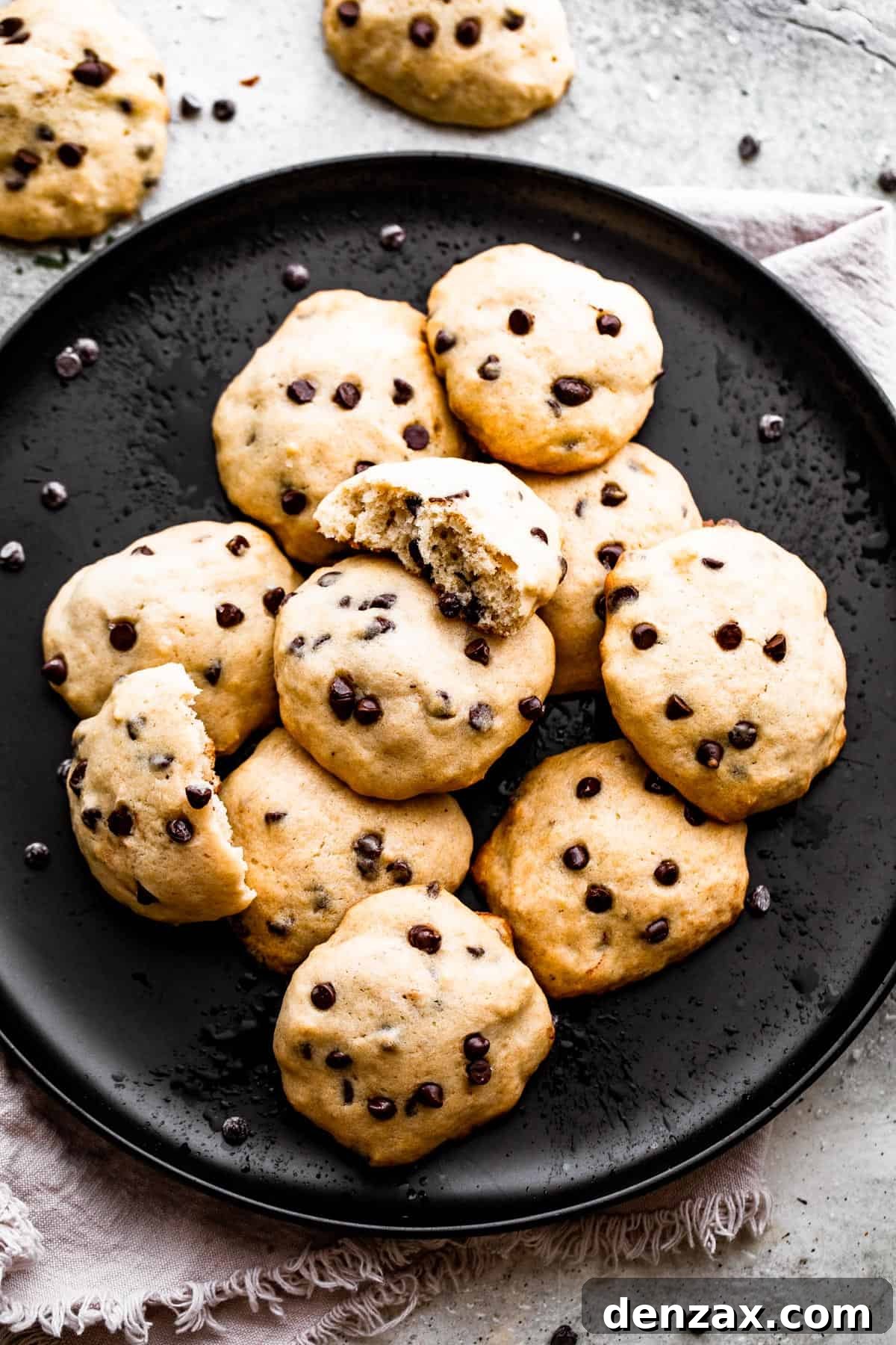 Close-up overhead view of baked banana chocolate chip cookies on a black plate, highlighting their golden edges and soft centers.