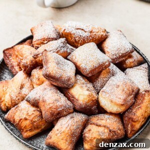 A plate of fried beignets, dusted with powdered sugar.