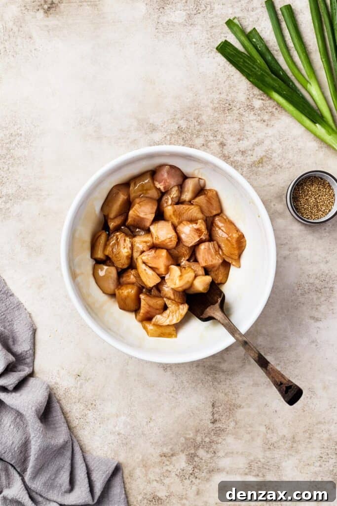 Chicken marinating in soy sauce in a white bowl, a crucial first step for flavor.