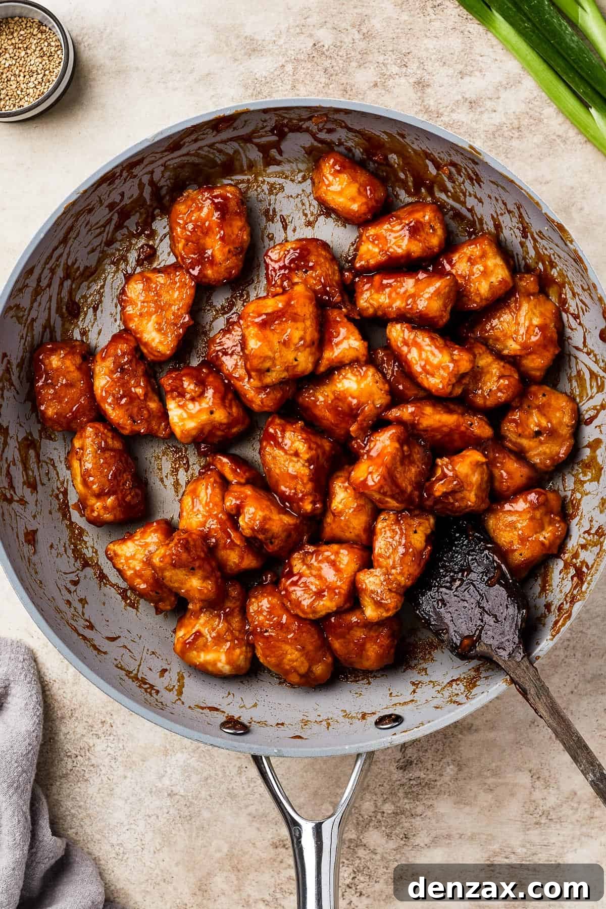 A skillet brimming with fried chicken coated in a luscious, glistening sweet and sour sauce.
