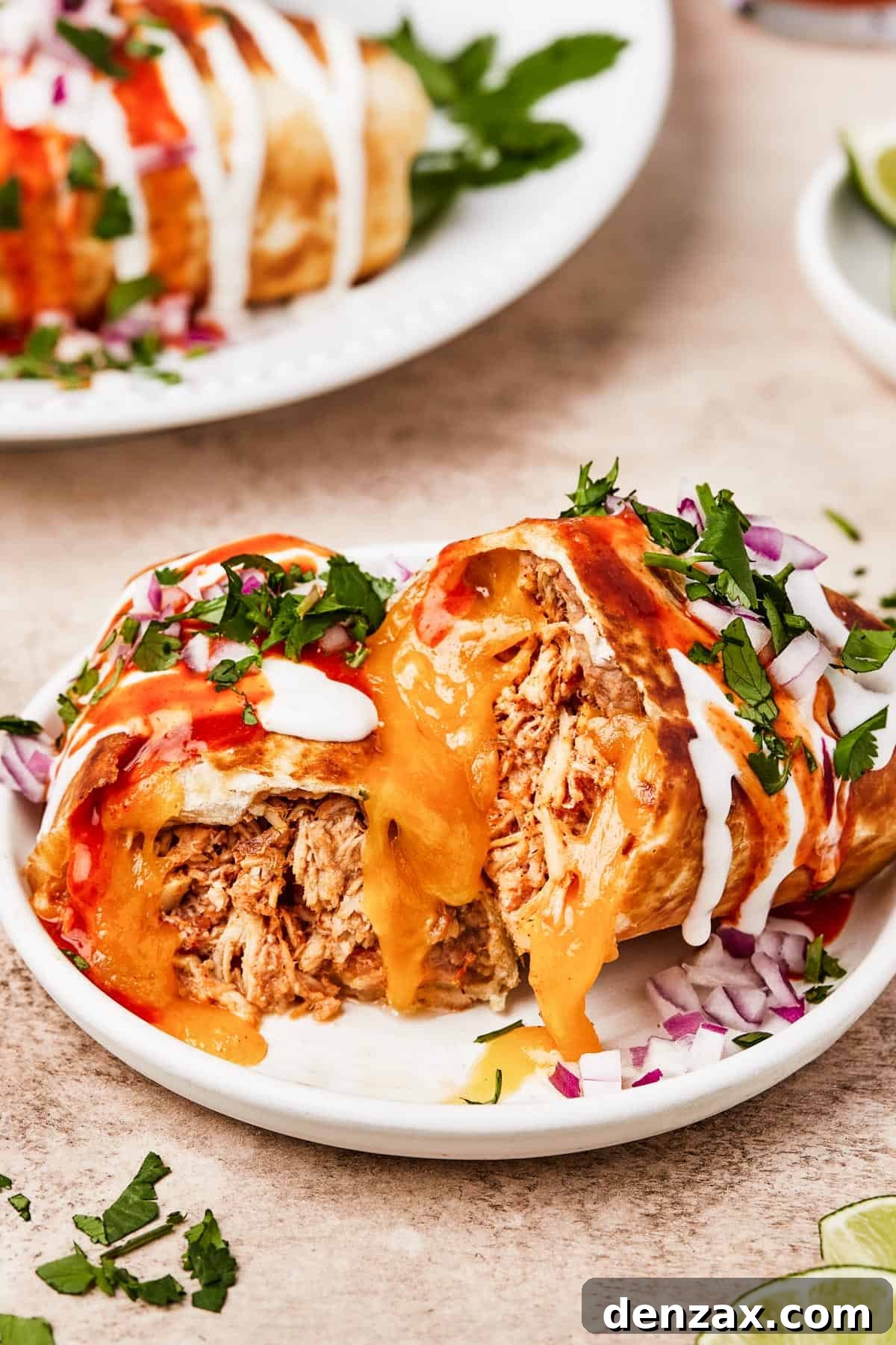 A plate with a chimichanga cut in half to show the savory chicken, bean, and cheese filling.