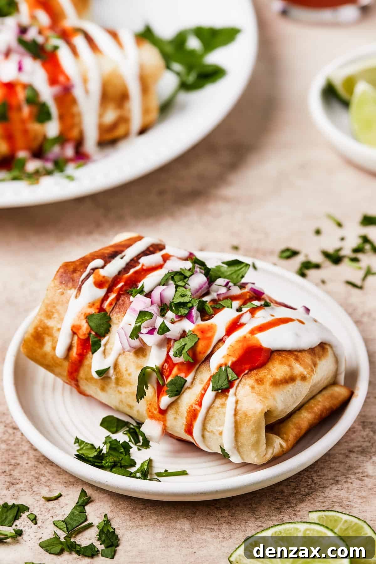Close-up shot of crispy, golden-brown chicken chimichangas topped with fresh sour cream, vibrant pico de gallo, and chopped cilantro.