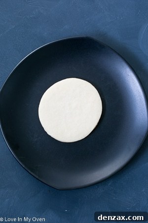 Step-by-step image showing white royal icing base applied to a cookie.