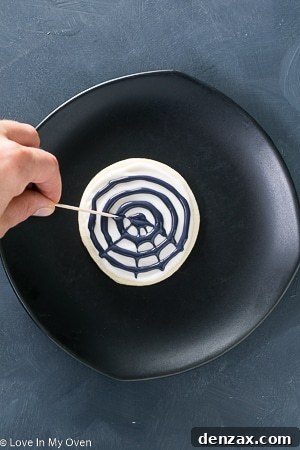 Step-by-step image showing the finished spiderweb design on a cookie.