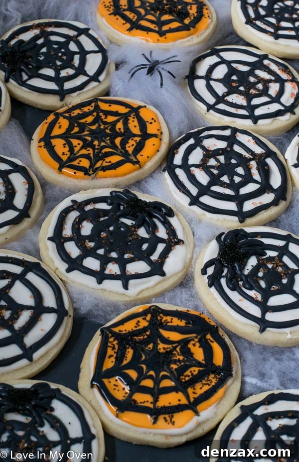 Close-up of a stack of freshly baked spiderweb cookies, showcasing the intricate royal icing design on a tender cream cheese base.