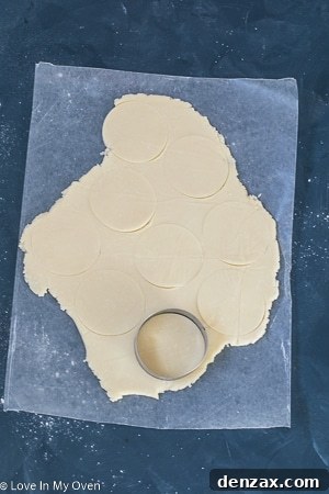 Two baked cream cheese cookies, one showing the lightly browned edge, cooling on a rack.