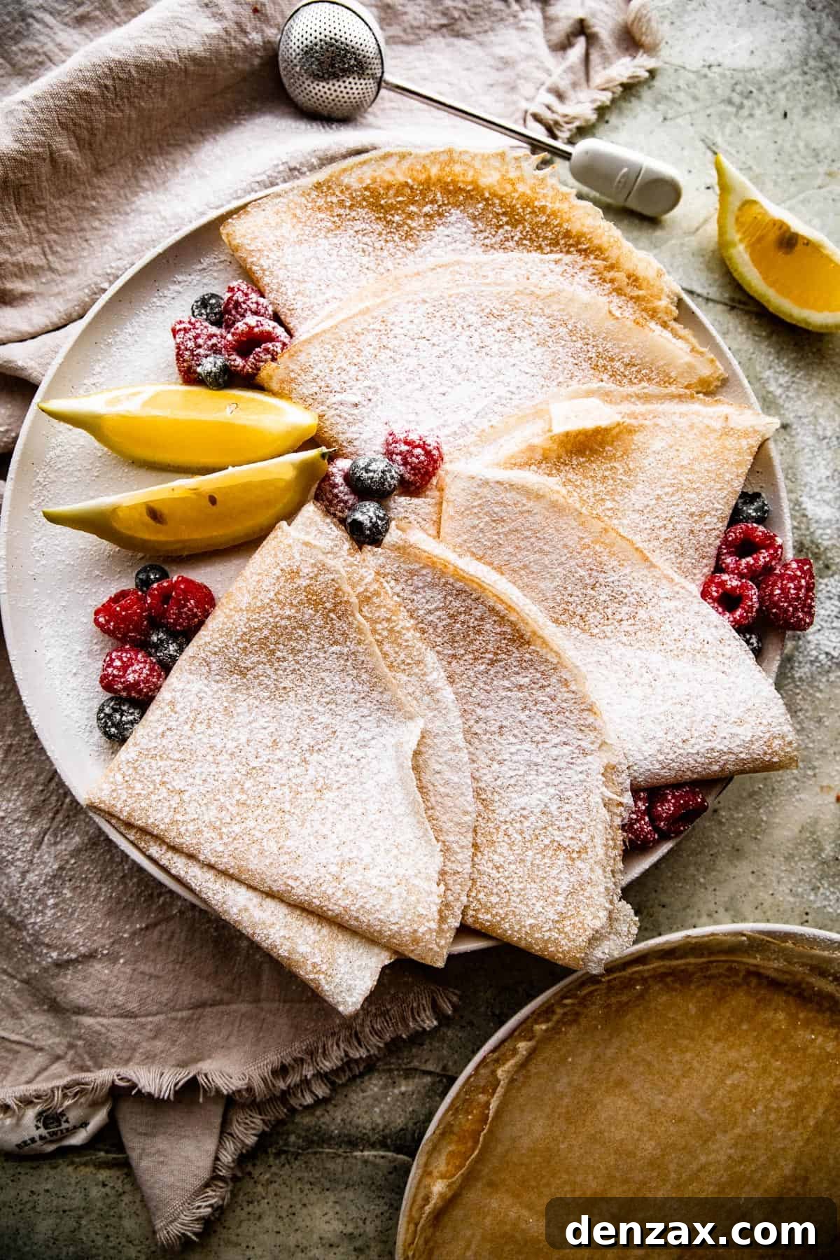 overhead shot of homemade crepes folded over and dusted with powdered sugar.