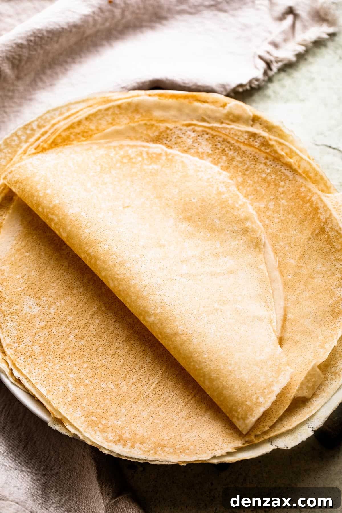 freshly made crepes set on a plate and half of the crepes folded over in half.