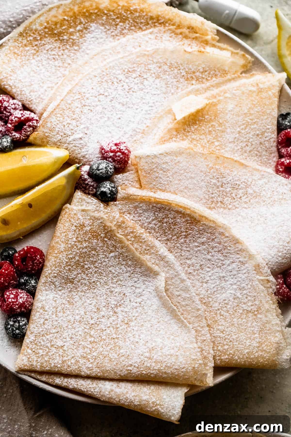 overhead shot of homemade crepes folded over and dusted with powdered sugar.
